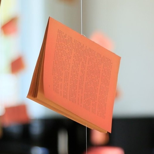 Ein rosa angemaltes Buch hängt an einer Schnur von der Decke.