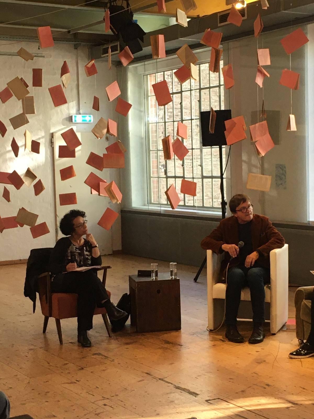 Zwei Menschen sitzen auf Sesseln im Brick-5 und hören aufmerksam zu.