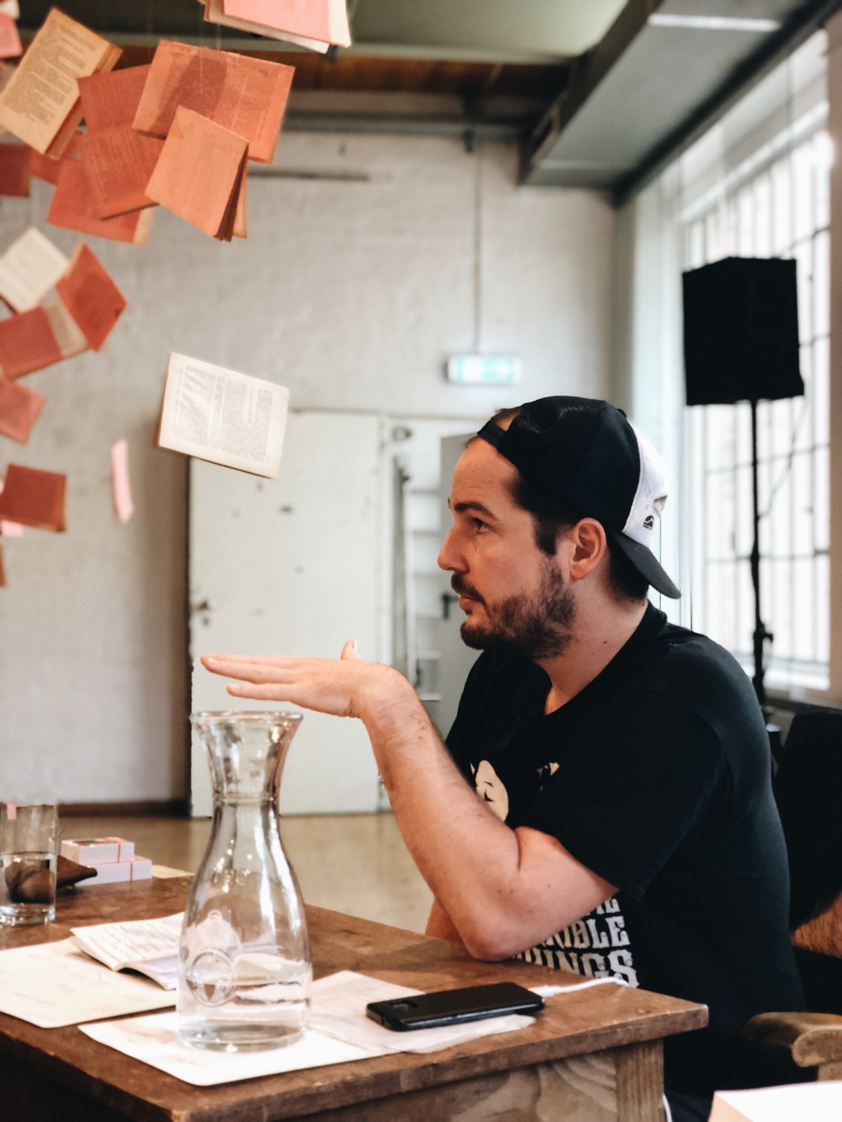 Max Czollek sitzt an einem Tisch und redet.
