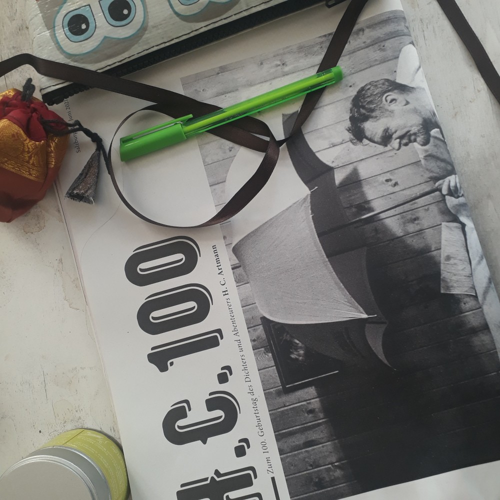 Eine Zeitschrift mit einem schwarz weißen Bild eines Mannes unter einem Regenschirm liegt auf einem Tisch.